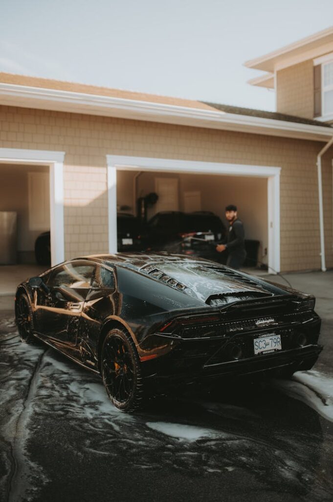 Person Washing a Black Lamborghini in Front of Building